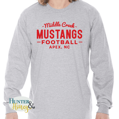 A gray ringspun cotton long sleeve tee with a red imprint that reads Middle Creek Mustangs Football Apex, NC.