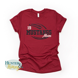 A red short-sleeve crewneck t-shirt with a two-color black and white glitter football with the text of Mustangs Mom running in the middle of the football.