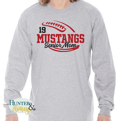 A gray long sleeve t-shirt with a red and black glitter football graphic with Mustangs Senior Mom cutting through the middle of the football and customized with a player's jersey number above Mustangs.