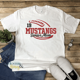 A white short-sleeve crewneck t-shirt with a two-color red and black glitter football with the text of Mustangs Senior Mom running in the middle of the football.