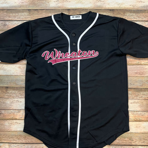 Wheaton Batton black glitter baseball jersey. This is the front of shirt featuring a two-color pink and white glitter script font Wheaton logo.