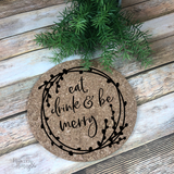 7" round natural cork trivet with black script "Eat, Drink, & Be Merry" graphic surrounded by an image of a berry laurel wreath border. 